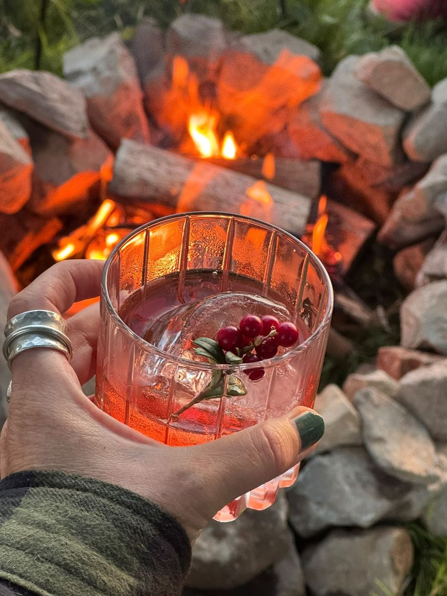 Un cocktail con bacche rosse davanti al fuoco