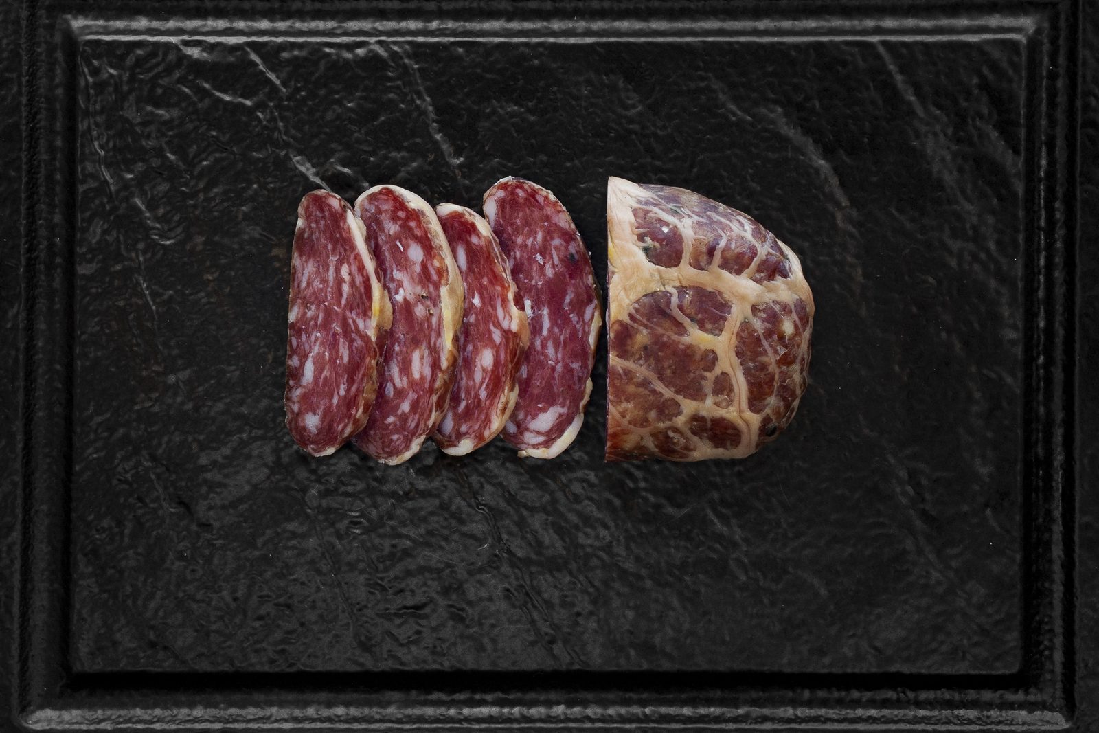 Fette di mortandela e una mortandela tagliata su una lastra di ardesia